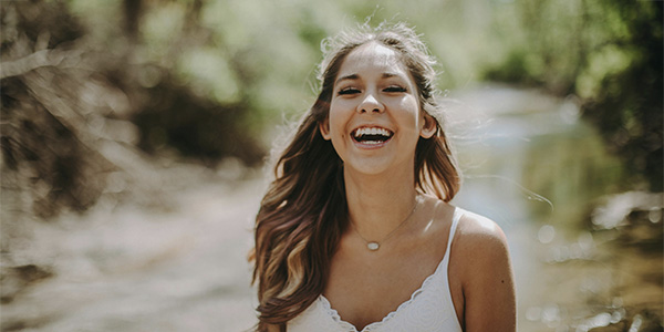 Woman outside on a walk smiling, represents how, at Evolve Psychological Services, we support individuals and help them reach their goals.