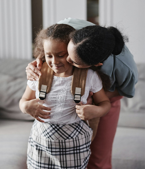 Mother kissing her daughter before school, represents how you can support your child through children & teens counseling in Montclair, NJ.