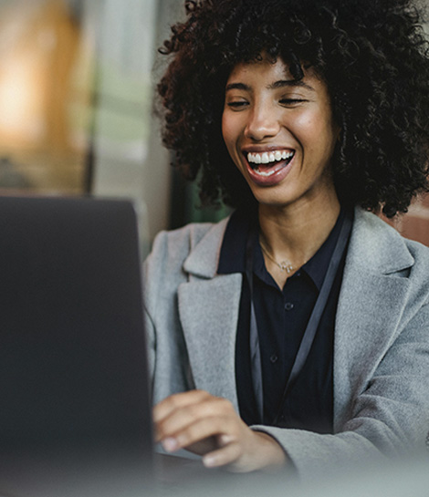 Happy woman working on her laptop, represents how an ADHD therapist can help you feel more confidence and grounded.