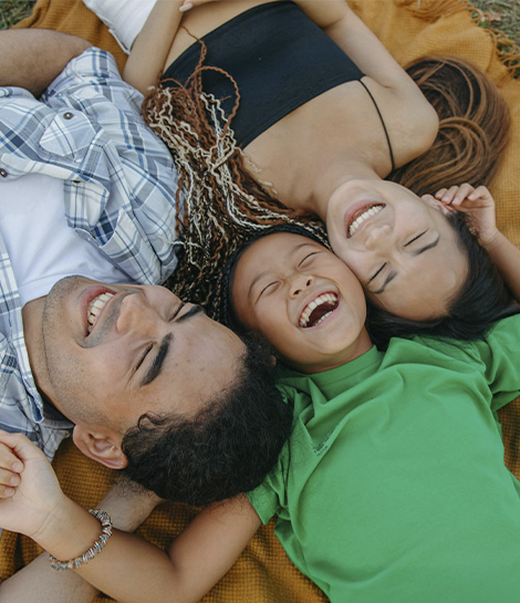 Happy lying down on s picnic blanket and laughing together, represents how family counseling can help you overcome your issues as a family.