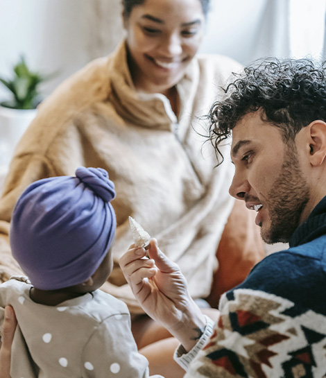 Happy parents taking care of their baby, represents how parenting coaching helps you feel more confident to overcome challenges as a parent.
